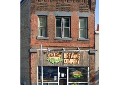 Two-story brick building with ground-floor business signage for "hop farm brewing company.